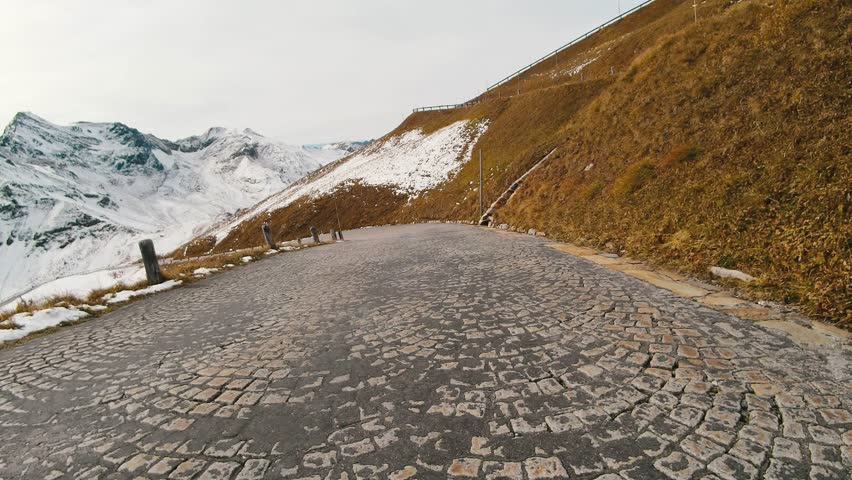 Car ride Point Of View, The Majestic Grossglockner Mountain Road in Austria, snow covered sharp peaks of the alpine mountains. POV shot of sport car or bicycle drives along the majestic and most