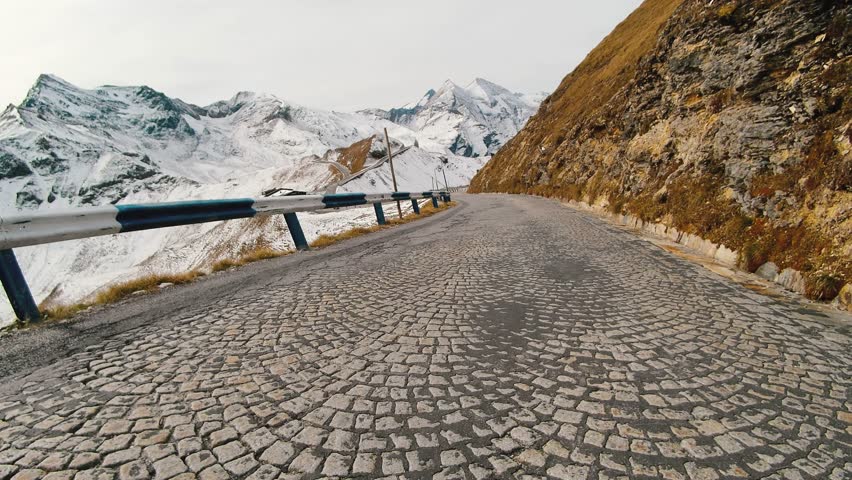 Car ride Point Of View, The Majestic Grossglockner Mountain Road in Austria, snow covered sharp peaks of the alpine mountains. POV shot of sport car or bicycle drives along the majestic and most | Shutterstock HD Video #1111588667