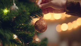 Close-up hand of woman decorating Christmas tree with baubles balls on the background of festive lights at home on calm winter evening, Christmas and new year concept, vertical view orientation - Powered by Shutterstock - Get 15% off with code: PIKWIZARD15