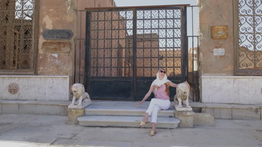 Woman is sitting near on a stairs with old Arabic ornaments. Touristic attraction. Cairo. Egypt. 