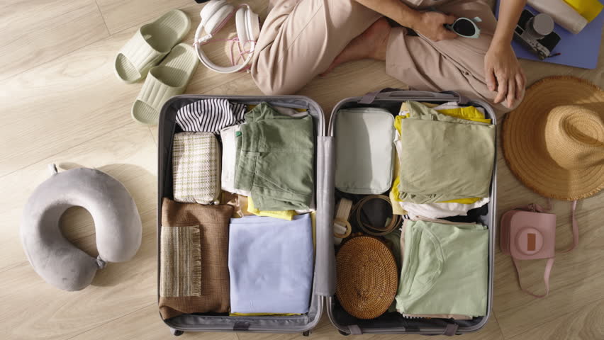 Packing suitcase top view. Woman packing suitcase for trip to beach. Organization of belongings for stress-free travel experience. Snorkeling mask and snorkel, summer vacation tropical packing feature | Shutterstock HD Video #1111591679