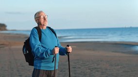 Smiling old man with Scandinavian walking stick dreaming admiring sunset sunrise sand sea beach closeup. Happy elderly grandfather enjoy healthy lifestyle outdoor sport activity contemplate seascape - Powered by Shutterstock - Get 15% off with code: PIKWIZARD15