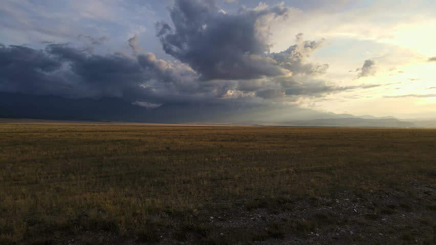 A drone view of a beautiful sunset in the valley in the fall. Incredible clouds on the horizon and mountains.