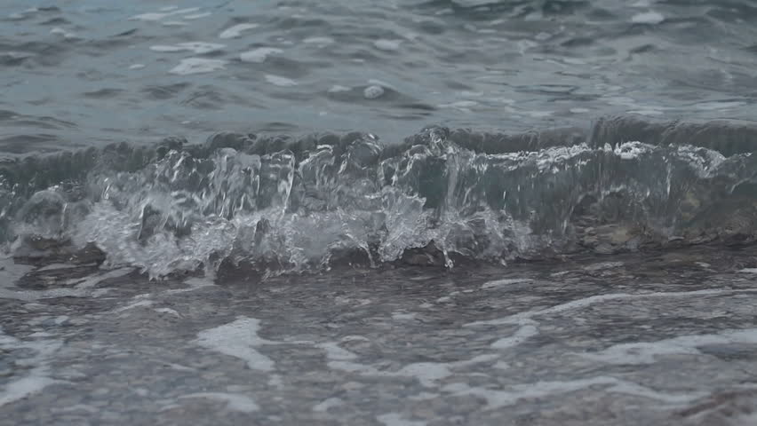 Slow motion shot of waves and sea foam crushing the pebbled beach in summer morning, selective focus | Shutterstock HD Video #1111594269