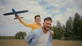 Happy fatherhood family smiling Caucasian male father joyful son piggyback dad back little boy child kid playing toy plane together pilot have fun flying fantasy outside field countryside park holiday - Powered by Shutterstock - Get 15% off with code: PIKWIZARD15