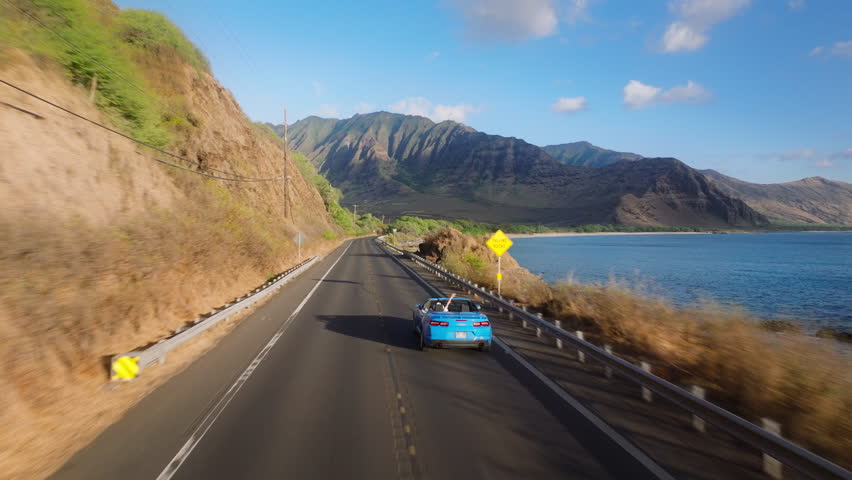 Aerial view sport car with tourist. Road trip, summer adventure. Beautiful nature of Hawaii tropical island in Pacific ocean. Blue convertible car driving on scenic road by West coast on Oahu island