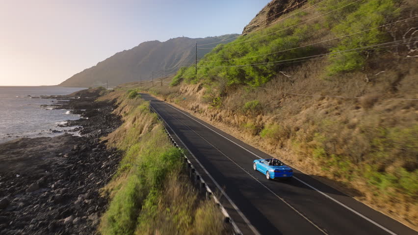 Aerial shot expensive blue luxury convertible vacation vehicle driving on sunny clean road highway Hawaii island. Happy tourists riding in blue sport car by mountain road. Joy future outdoor adventure