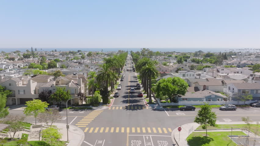 Drone flying over Newport Beach road with traffic, Corona Del Mar, California, West Coast, USA. Residential houses and private villas with tall palm trees. Long avenue stretching to Laguna Beach Royalty-Free Stock Footage #1111595283
