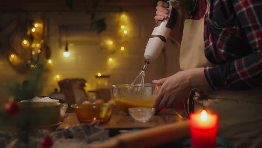 Cookie. A girl baker in baker's clothes beats the dough with a blender whisk at her workplace. Camera in motion, a craftswoman uses a kitchen blender in home cooking, honors family traditions, a gift