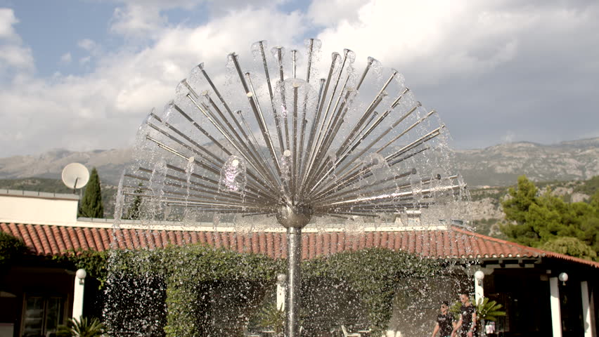 City fountain takes the form of a dandelion flower, offering delightful and enchanting sight. Design captures spirit of summer day, warmth and leisure in picturesque settings of Southern Europe. Royalty-Free Stock Footage #1111599765