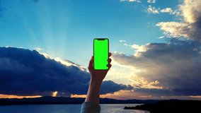 a green screen smart phone on man hand with beautiful sky time laps background.