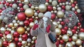 Beautiful model woman in mask student talks on the phone with her friends or parents online, video conference, Christmas week 2024, gifts and Christmas decoration, new year mood, holidays
