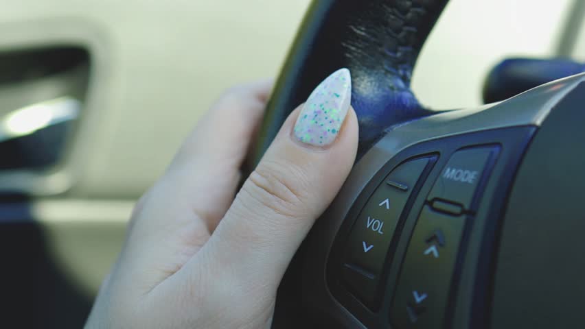 female hand turns on the radio in the car, beautiful fingers