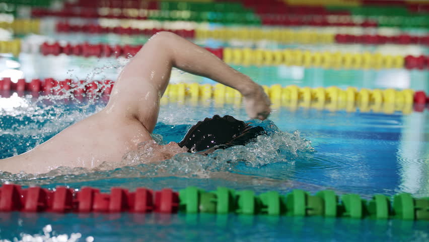 Male competitor in front crawl swimming race , performing freestyle arm movement, body rotation and breathing technique, tracking close up shot.