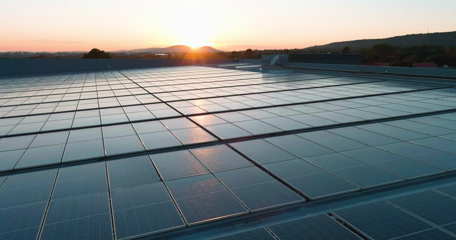 Aerial.  Sunlight catching solar power panels on top of a building in South Africa. Green renewable energy. Climate change, Global warming