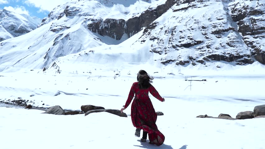 Slow motion shot of teenager Indian girl raising hands in front of snow covered mountains in Lahaul, India. Girl in mountains during frosty Sunny day. Royalty-Free Stock Footage #1111614585