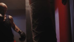 A middle aged bald boxer hitting the bag - Powered by Shutterstock - Get 15% off with code: PIKWIZARD15