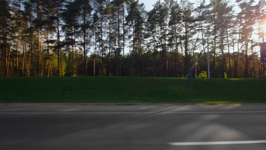 Highway out of town. Two lane freeway road. Traffic barrier guard rail along roadway. View through side window on passenger seat of car in motion. Spring roadway in april, evening. Trees on background Royalty-Free Stock Footage #1111615605