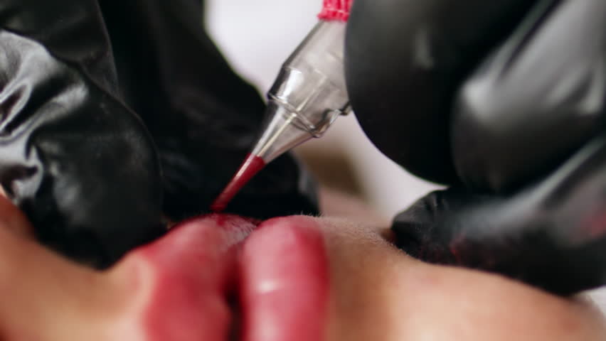 Permanent makeup procedure applying pink color pigment using tattoo machine in beautician salon. Microblading tattoo lips. | Shutterstock HD Video #1111622095