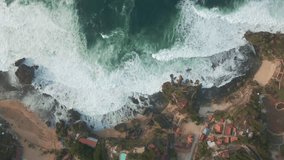 Aerial top down view of ocean wave crashing onto tropical beach