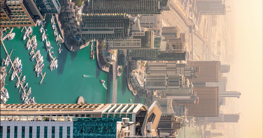 Vertical timelapse of futuristic Dubai Marina and Yacht club at Jumeirah Beach. Skyscrapers and luxury yachts on pier in man made lake in UAE. Famous tourist view of city center and desert road.