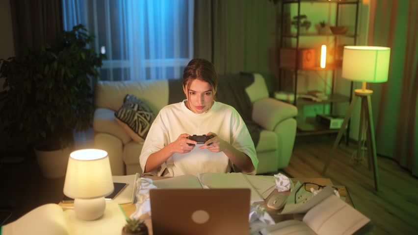 Excited cute young woman with joystick controller playing video games on laptop at late night alone Upset female lose the competition at home Defeat Game addiction concept | Shutterstock HD Video #1111635077