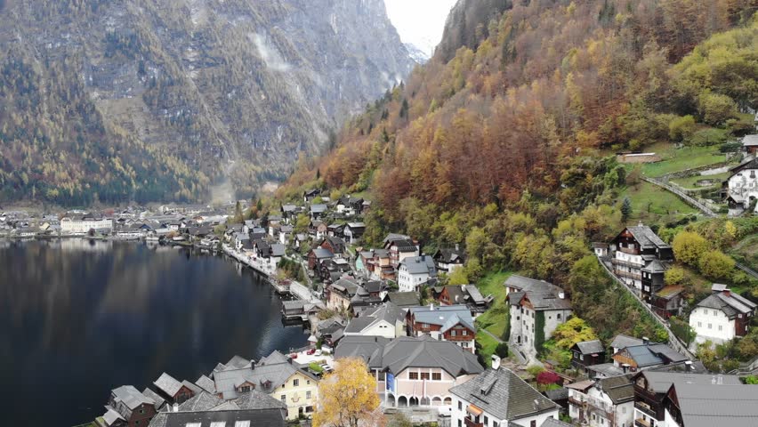 Aerial view of famous town Hallstatt in Salzkammergut, Upper Austria. Lake and mountain sides covered with yellow autumn trees. 4K