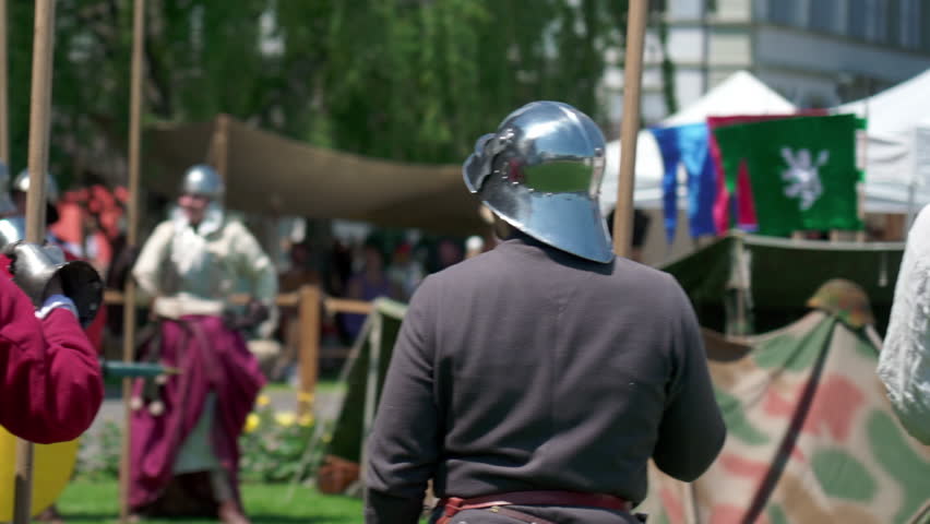 Back of Medieval Soldiers with Spears and wearing steel helmets on standby at Historical Reenactment Fair