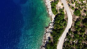 4K Drone footage of car moving by the sea curved road near a tranquille waves on the Greek coast on Cephalonia island. Transportation, nature concept.