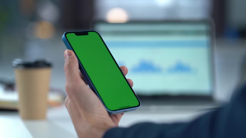 Close-up Of Mobile Phone With Green Mock-up Screen In Men's Hands On Desktop Background. Man Using Smartphone, Browsing Internet, Social Networks, Financial Reports. | Shutterstock HD Video #1111640795