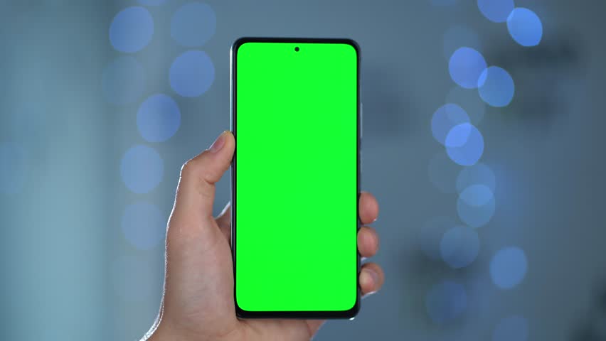 Close-up Of Phone With Green Mock-up Screen In Men's Hands Against Blurred Lights. Man Performing Swipe, Scroll, and Tap Gestures to Smartphone Display | Shutterstock HD Video #1111640801