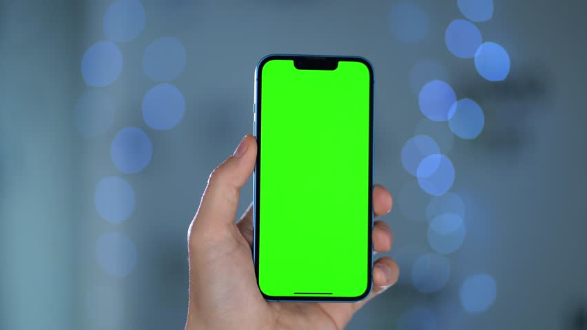 Close-up Of Smartphone With Green Mock-up Screen In Men's Hands Against Blurred Lights. Person Performing Swipe, Scroll, and Tap Gestures to Phone Display  | Shutterstock HD Video #1111640807