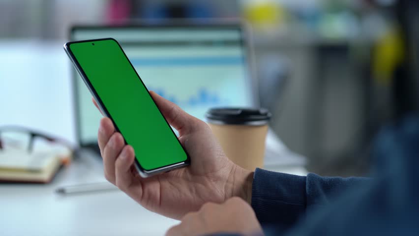 Close-up Of Smartphone With Green Mock-up Screen In Men's Hands On Desktop Background. Man Using Mobile Phone, Browsing Internet, Social Networks, Financial Reports. | Shutterstock HD Video #1111640815