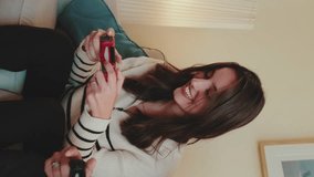 Vertical video, Young couple playing console videogame with joysticks having fun