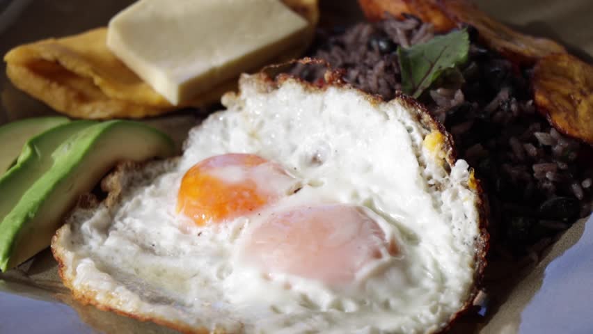 Balanced, healthy, Costa Rican traditional full breakfast with fried eggs, avocado, rice and beans, tortilla and cheese.