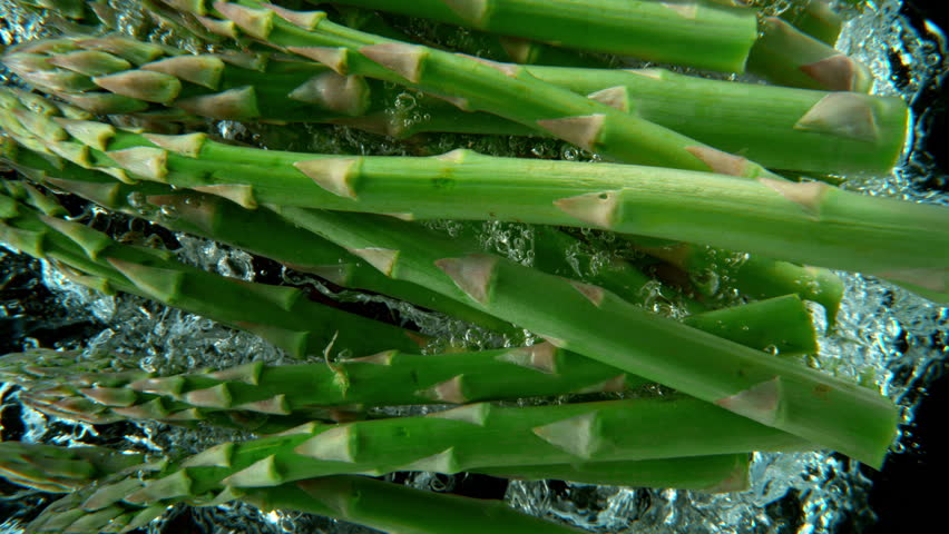 Super slow motion shot of falling asparagus into water, black background. Filmed on high speed cinematic camera at 1000 fps. - Powered by Shutterstock - Get 15% off with code: PIKWIZARD15