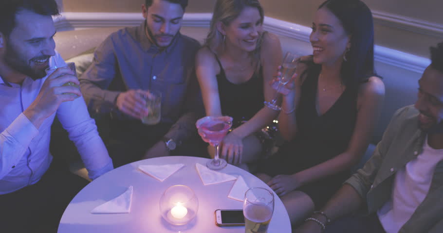 Friends, drink and laugh for toast in nightclub for celebration, event or conversation together. Man, woman and smiling for talk with glass, cocktail or alcohol for cheers with LED, light or colorful