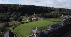 4K summer morning aerial footage of green forest, church complex and hotel bungalows
