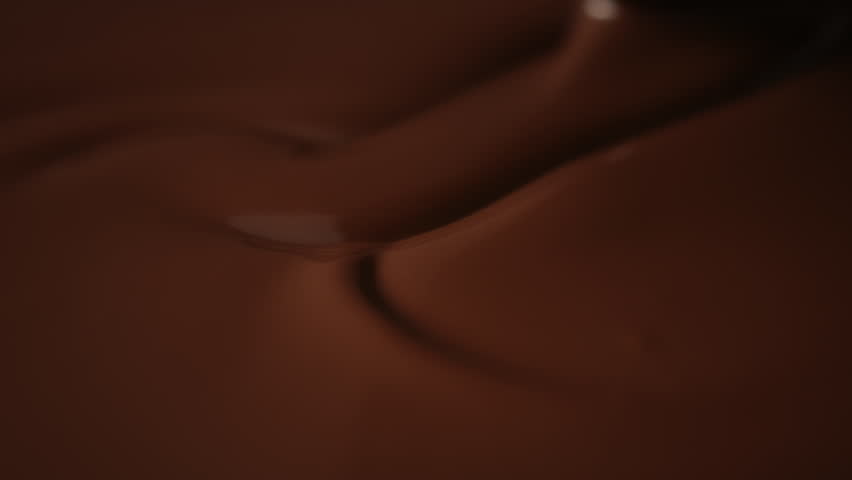 Close-up stirring melted chocolate with pastry spoon, hot liquid chocolate in bowl, mixing molten milk chocolate fondue. Cooking handmade chocolate bars, dessert or candies. Confectionery slow motion | Shutterstock HD Video #1111650157
