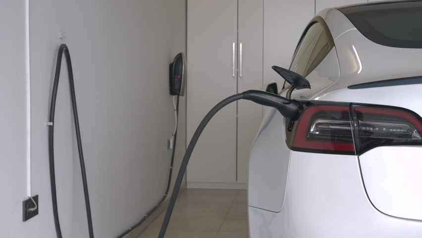 CLOSE UP: Woman approaches an electric car and disconnects it from charging unit in home garage. Young lady sits into white electric vehicle that is ready to drive with a fully charged engine battery | Shutterstock HD Video #1111650213