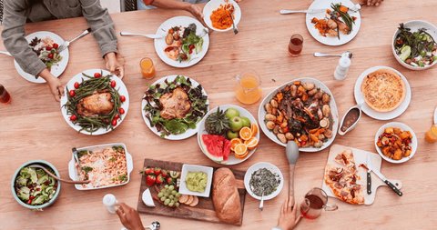Above, food and dinner with hands at birthday party or event with family, friends and healthy meal. Top view, people, lunch or brunch with beverage, celebration or bonding at dining table of home Video Stok