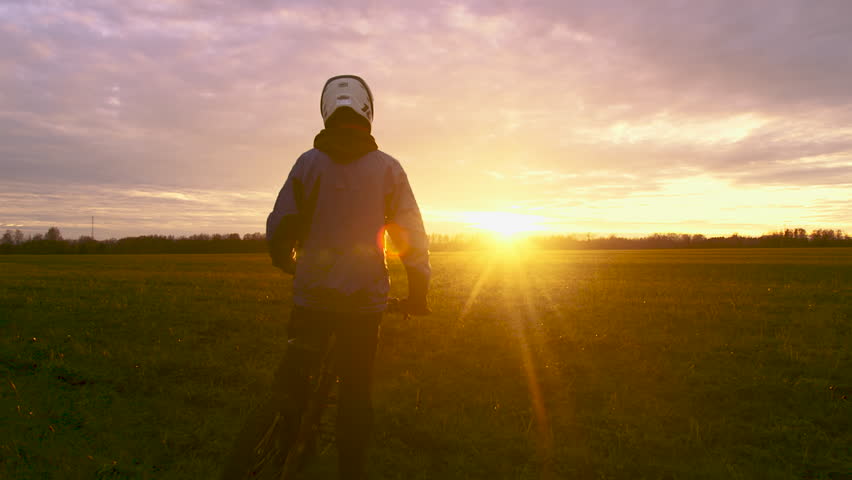 Cyclist In Helmet Riding On Sunset. Sport Recreation Bike Cycling On Sunset Time. Mountain Bike Passes a Field Flooded with the Light of the Setting Sun. Active Recreation, Adventures | Shutterstock HD Video #1111663323