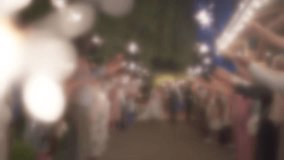 Blurred slow motion, wedding couple is hugging. Guests with sparklers on night party. Funny event time. Slow motion video. Out of focus video.
