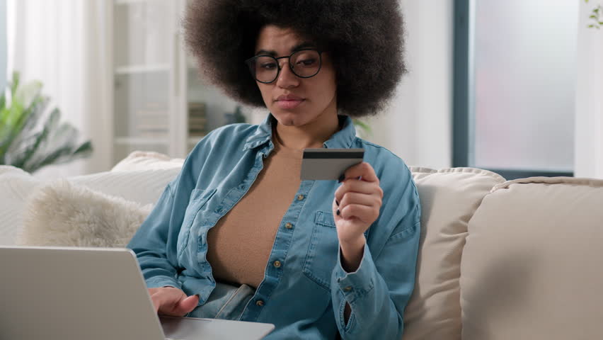 African American thoughtful client female buyer user lady girl thinking pensive decide ponder shopping with laptop computer and bank credit card think payment internet online buy goods order at home Royalty-Free Stock Footage #1111671157