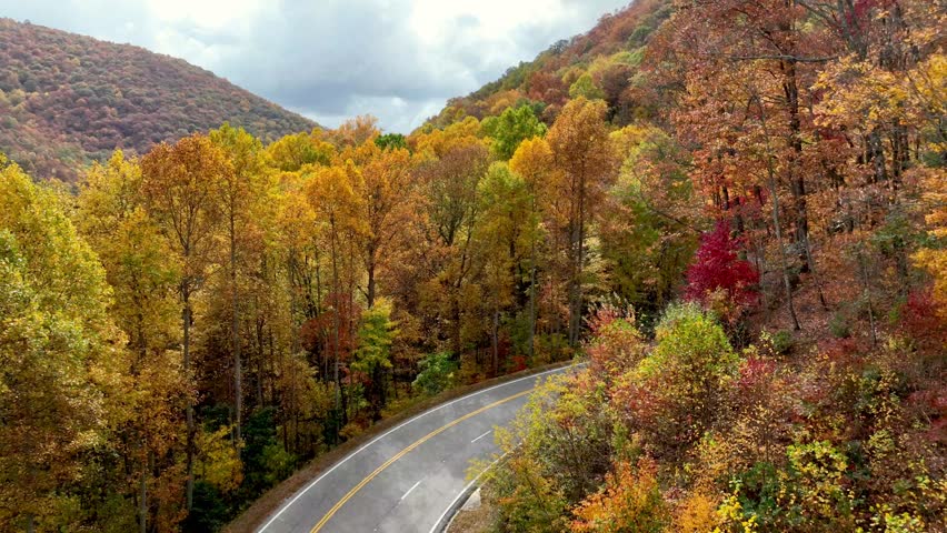 aerial pullout fall foliage with car and motorcycle along roadway in the mountains of northern georgia