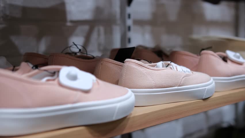 Assortment of comfortable shoes is lined up on shelf of store. Variety of sports shoes provides many options to choose from. Suitable for shopping inspiration or advertising sneakers and other shoes.