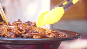 Closeup shot of cooking barbeque meat grilled on grill pan using food tongs