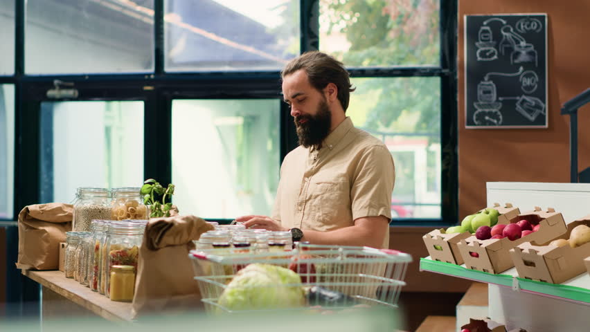 Young customer shopping in eco store, looking at fresh organic produce locally grown from farmers. Person visiting bio zero waste supermarket to buy food additives free pasta or vegetables.