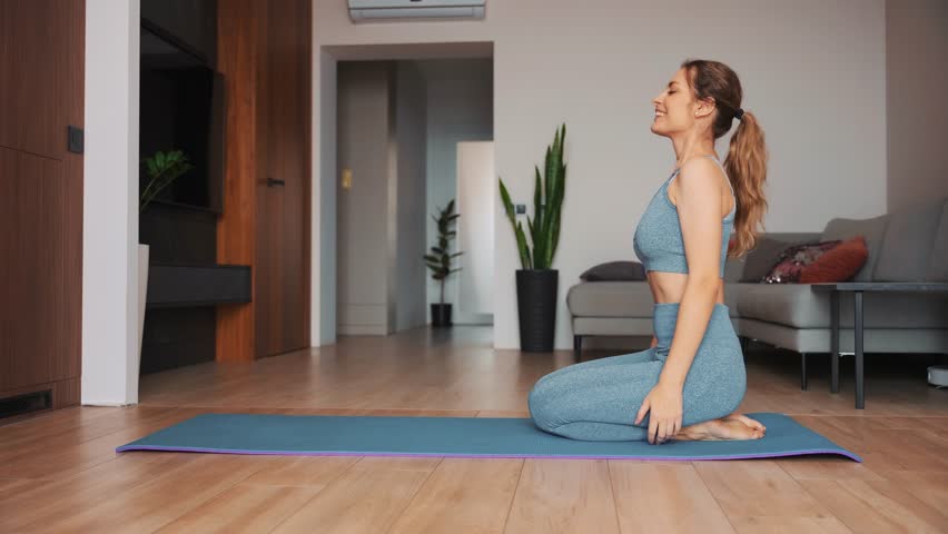 Joy young happy woman smiling face going to do sports at home puts carpet mat on floor trendy sportswear suit blue top leggings. Girl sitting meditating in living room. sport fit yoga workout fitness | Shutterstock HD Video #1111680761