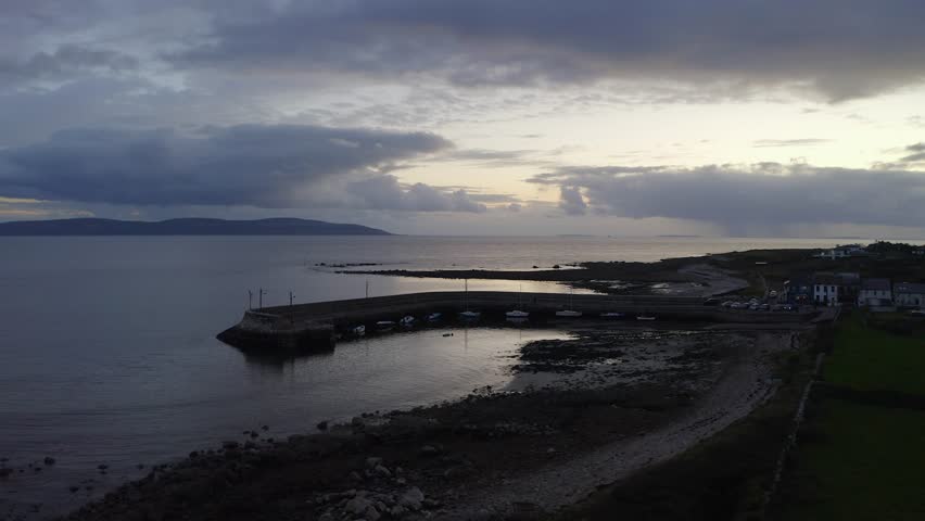 Aerial trucking pan of Barna pier at blue hour dusk, reveals quaint town